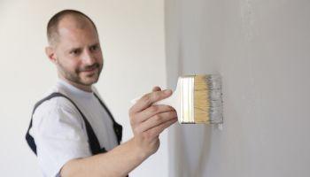 Man Touching Up Faux Concrete Wall Paint with Paint Brush